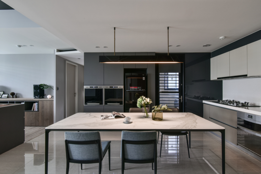 空間以灰黑色深色調為主,廚具選擇稍暖色調的門片,搭配顏色較亮的餐桌及餐椅,讓空間不會過於黯淡