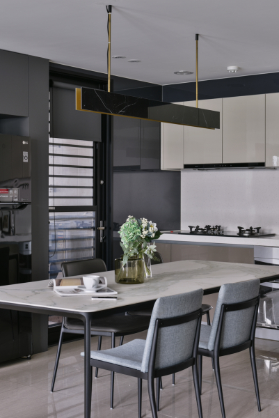 空間以灰黑色深色調為主,廚具選擇稍暖色調的門片,搭配顏色較亮的餐桌及餐椅,讓空間不會過於黯淡