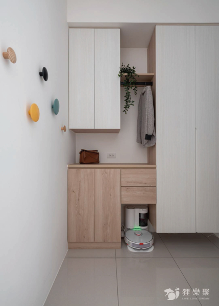 空間整體以白色和淺色木紋為主，搭配顏色較鮮艷的吊掛物件，增添空間的趣味，同時規劃平台及鐵件吊衣桿方便吊掛外出衣物，增加進出時的便利性