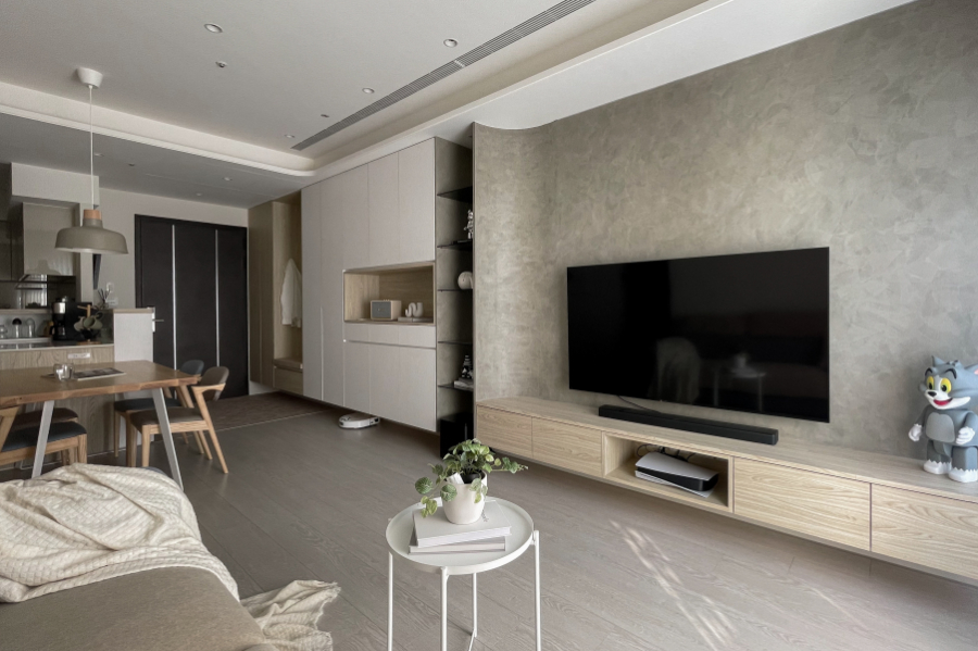 在天花板與電視牆中融入圓弧造型,電視牆面採用較有個性的灰色塗料,在溫暖的空間點綴視覺主角,使整體色調更加柔和