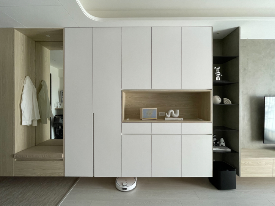 空間整體以白色與暖色木紋為主,玄關櫃結合收納及展示櫃,作為空間區分緩衝,天花板的弧形設計讓空間不感受壓迫且達到平衡