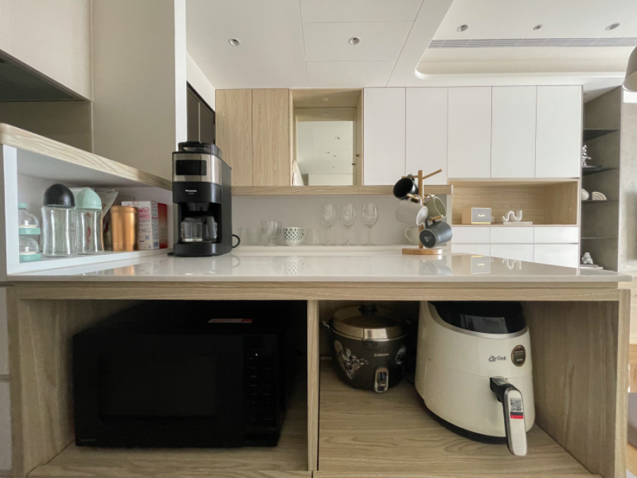 整體空間以白色搭配暖色系木紋,在設計上顧及了使用性,規劃為開放式中島,檯面上的收納設計,可收納小家電等物品,讓空間的視線範圍更為清爽整潔,同時也可作為備餐使用