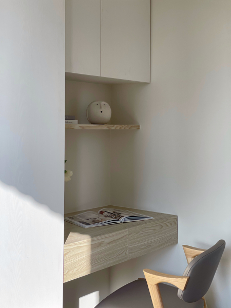 牆面大面積留白不特別跳色,搭配暖色系木紋,呈現空間沉靜感,臥榻設計可收納物品,同時也方便留宿的客人使用