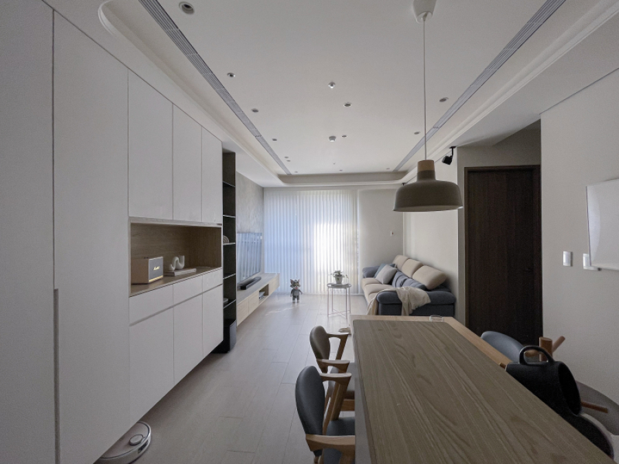 空間整體以白色與暖色木紋為主,玄關櫃結合收納及展示櫃,作為空間區分緩衝,天花板的弧形設計讓空間不感受壓迫且達到平衡