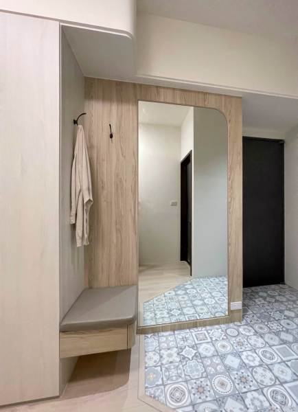 空間整體以淺色木紋為主,玄關使用大面積花磚做區隔,搭配大面明鏡使空間視覺更為寬敞且豐富,加入弧形設計的小巧思增添空間的柔和度